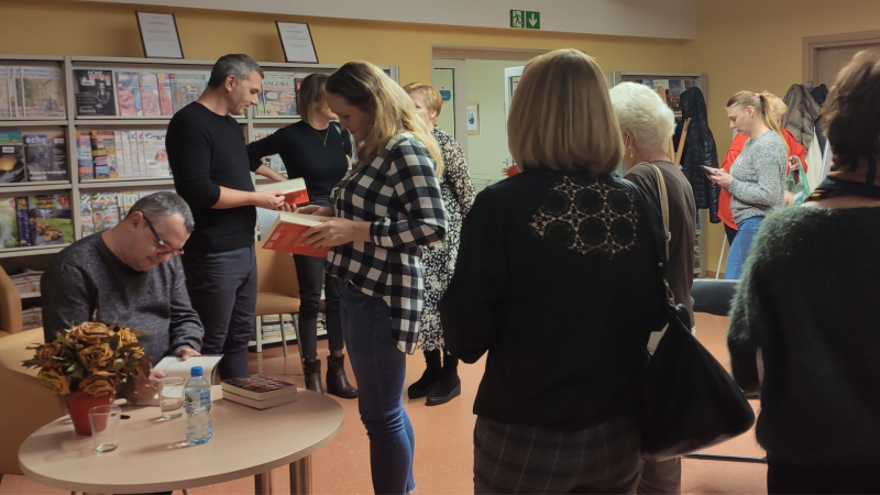 Zdjęcie kolorowe, spotkanie autorskie z Jarosławem Czechowiczem w Bibliotece, rozdawanie autografów